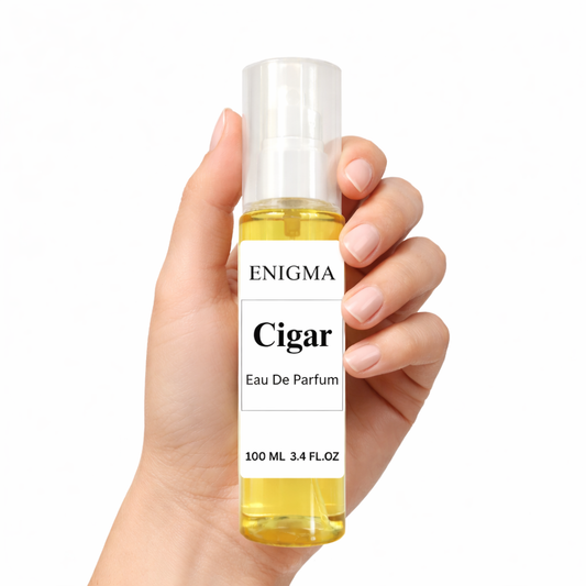 Hand holding a bottle of Enigma Cigar Eau De Parfum against a white background